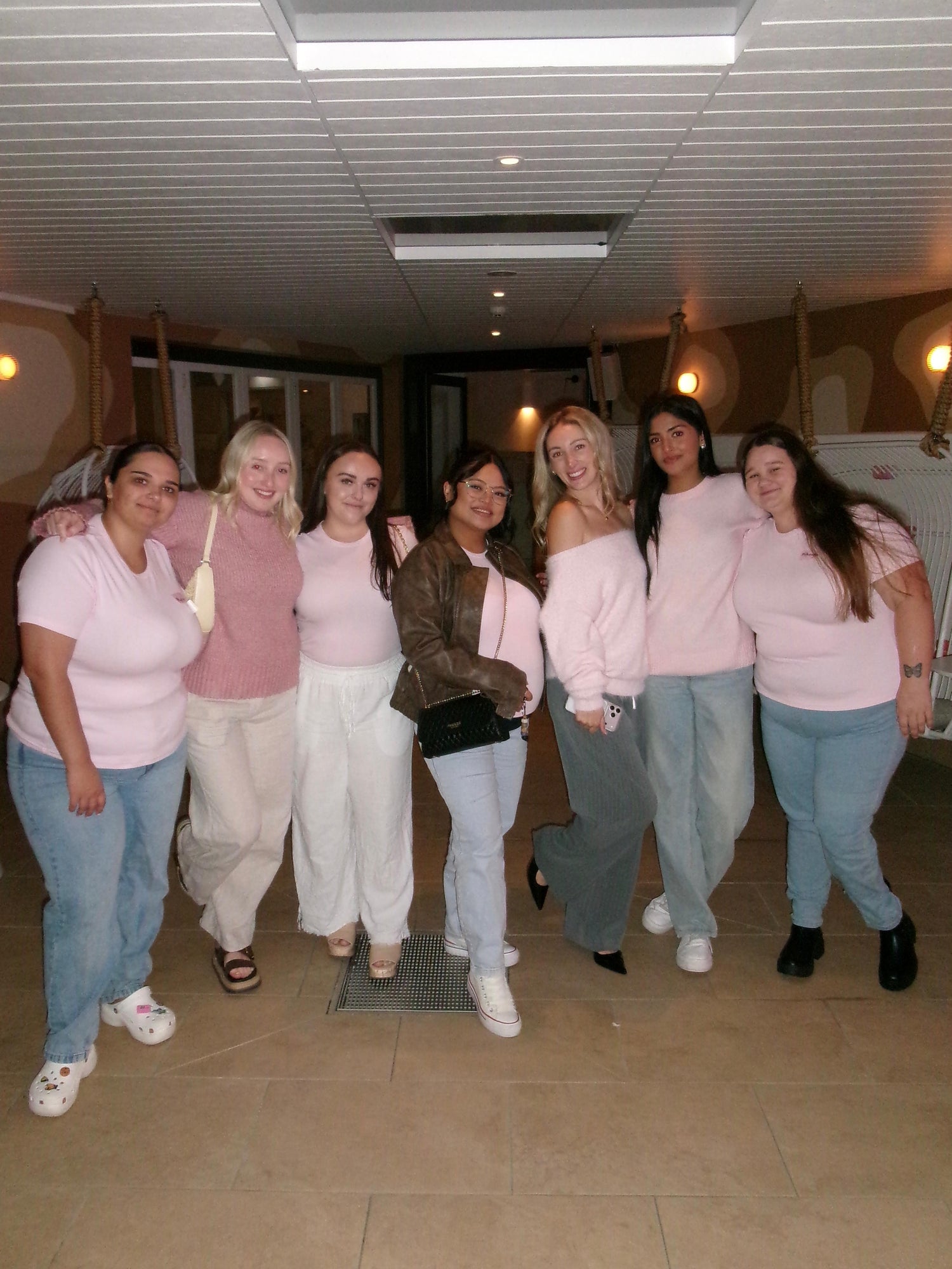 Group of women smiling together for a group photo at a The Girls Who Gather social event, celebrating friendship, community and meaningful connections in a warm indoor venue.