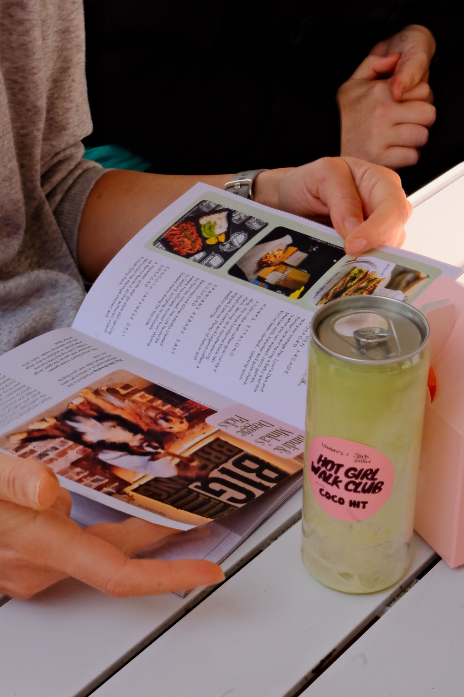 A branded COCO HIT drink at The Girls Who Gather Hot Girl Walk Club, with attendees browsing a menu in the background. Community event on the Central Coast bringing women together through social walks, conversation and local business partnerships.