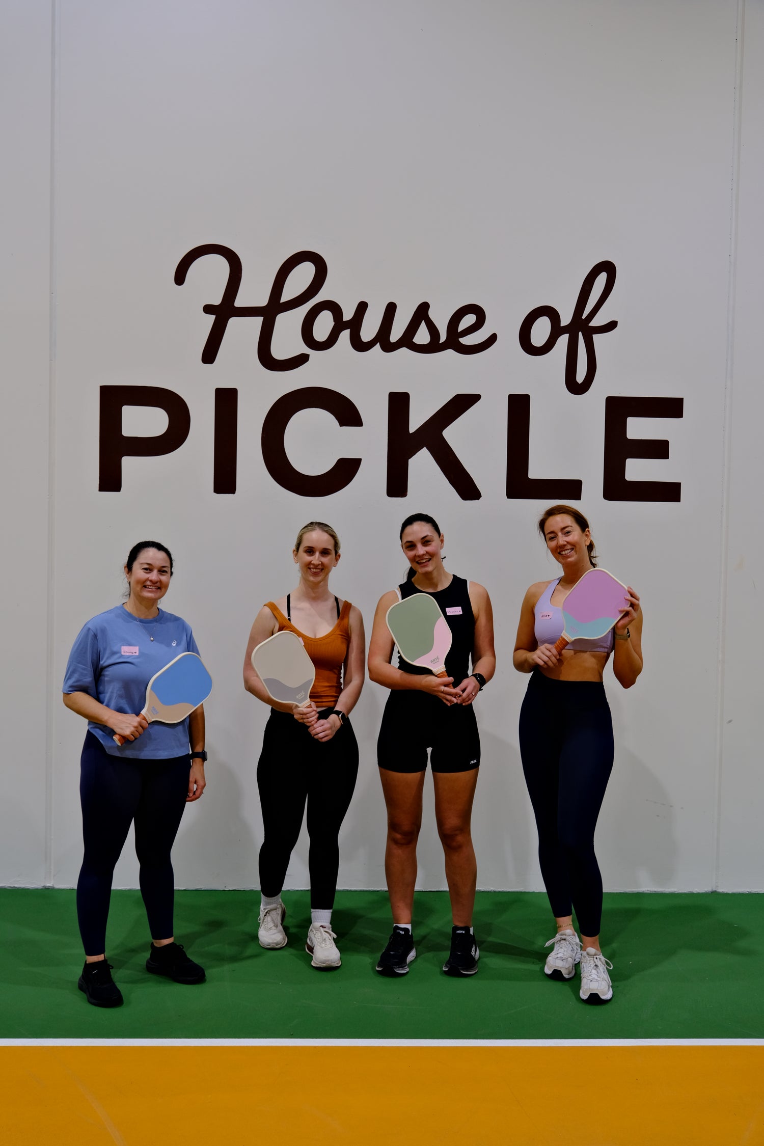 Four women posing with pickleball paddles at House of Pickle during a The Girls Who Gather women's pickleball social event on the Central Coast. Beginner-friendly community event focused on fitness, friendship and connection.