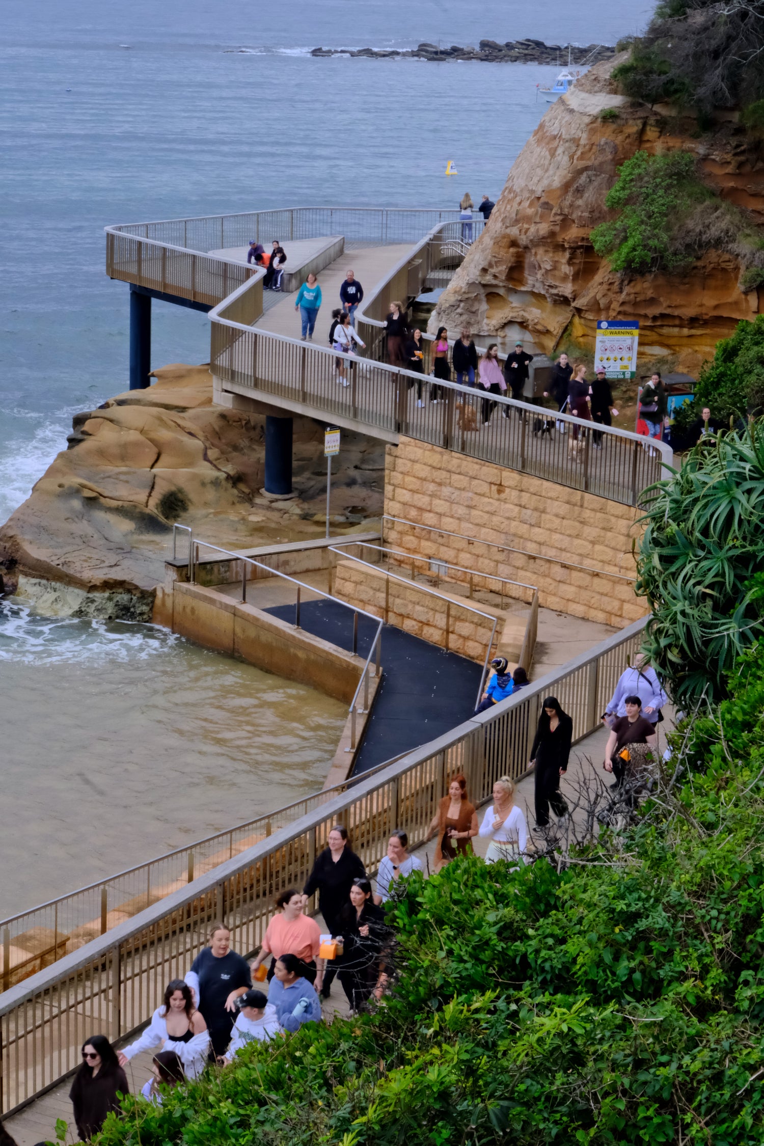 Women walking together along the Terrigal coastal boardwalk during a The Girls Who Gather Hot Girl Walk on the Central Coast, enjoying ocean views, fresh air and meaningful connection.