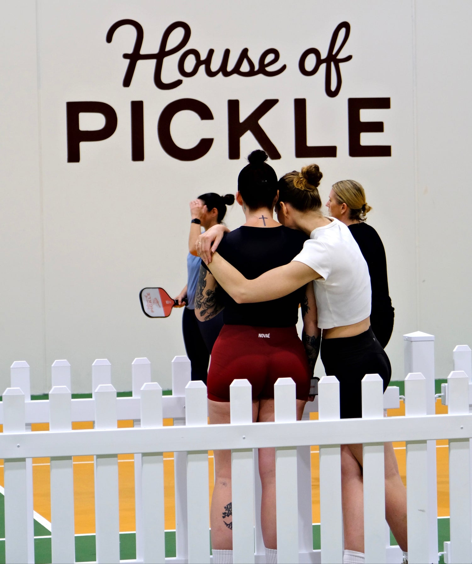Women sharing a supportive hug during a The Girls Who Gather pickleball event at House of Pickle on the Central Coast. A candid moment highlighting friendship, connection and community through women's social events.