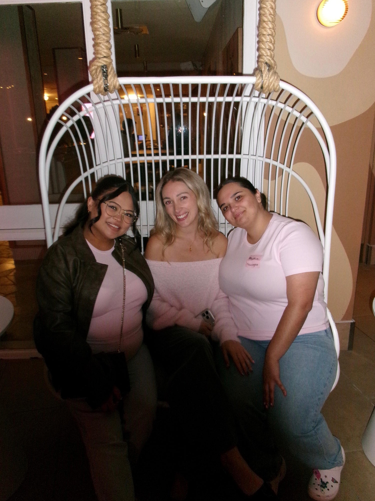 Three women smiling together on a hanging chair during a The Girls Who Gather social event on the Central Coast, celebrating new friendships, connection and a welcoming women's community.
